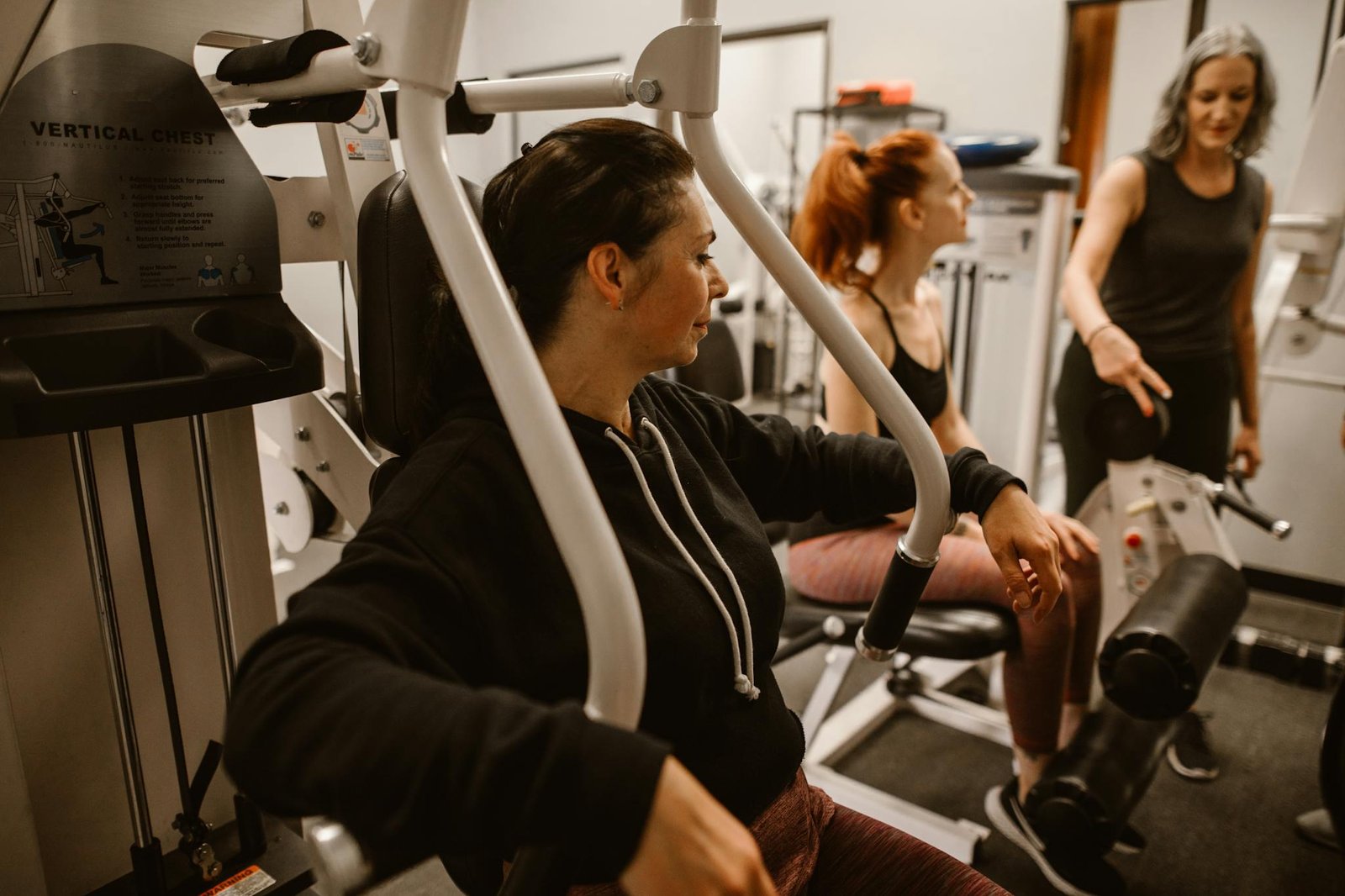 Adult women in a gym focused on fitness and health, using workout equipment.